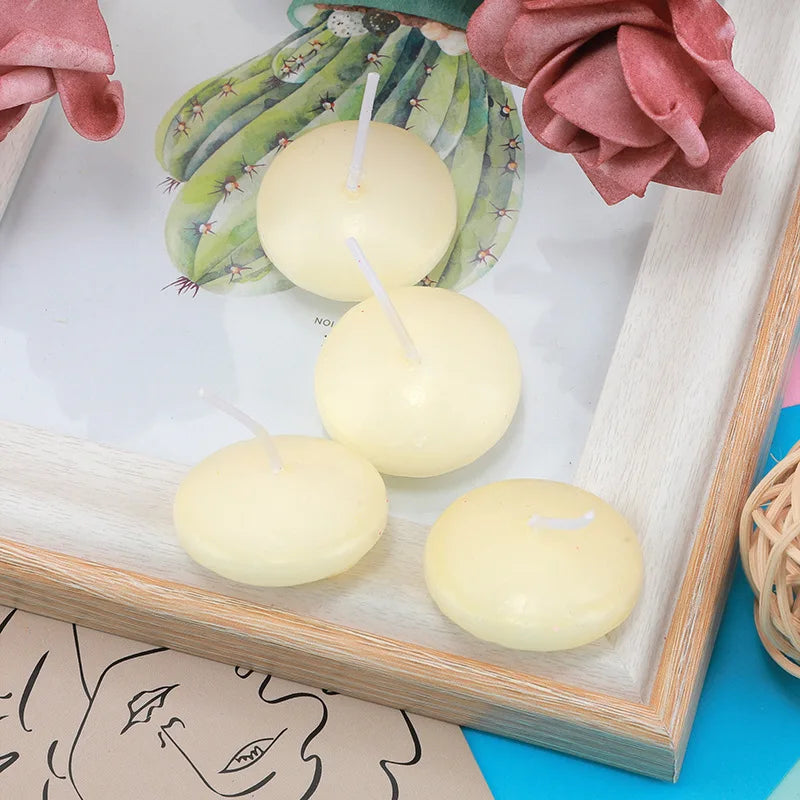 A collection of creamy yellow floating candles displayed in a wooden frame with pink and green floral accents.