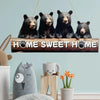 A rustic wooden inspirational hanging sign featuring four bear figures with paw prints, displayed on a light blue wall.