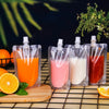 Several clear reusable pouches contain various colorful liquid drinks like orange juice, pink, and red juice on a wire rack.