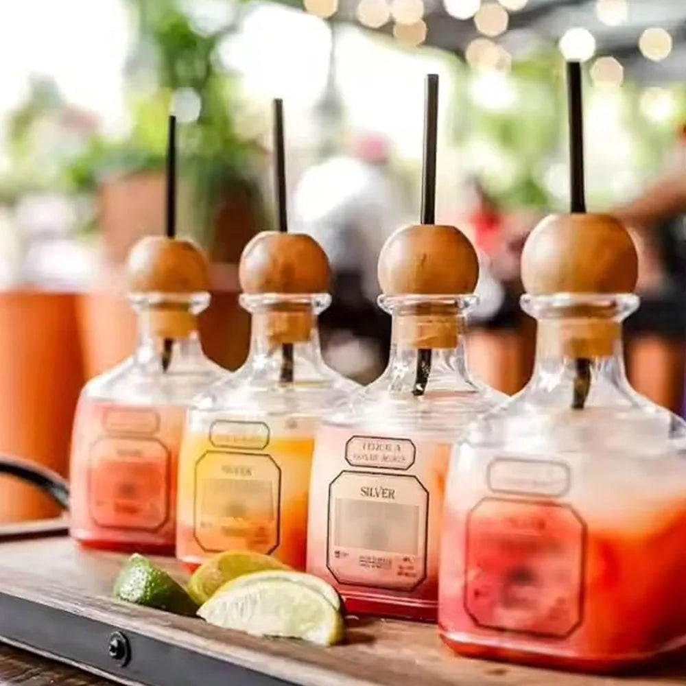 A glass bottle filled with red liquid and lime slices sits next to a reusable plastic drinking bottle.