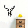 Black metal deer head wall sculpture with antlers mounted on a white wall above a wooden dresser.