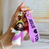 A hand holds a silicone keychain featuring a Jesus figure and a pink strap with the word Jesus you.
