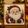 A framed painting depicting Santa Claus with a white beard surrounded by red and green pearls and foliage.