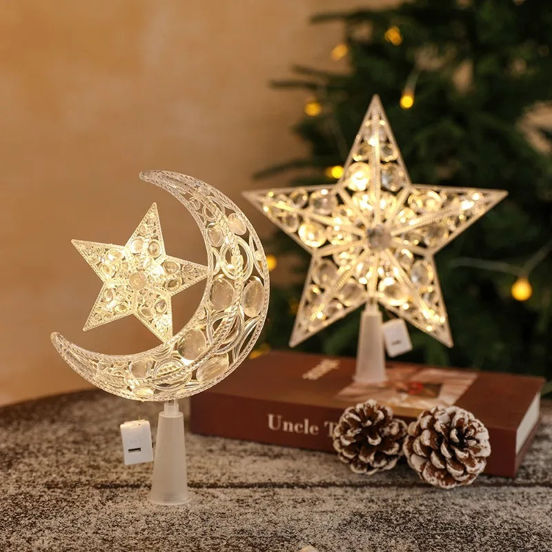 A decorative LED Christmas tree star topper shaped like a crescent moon, resting on a dark surface.