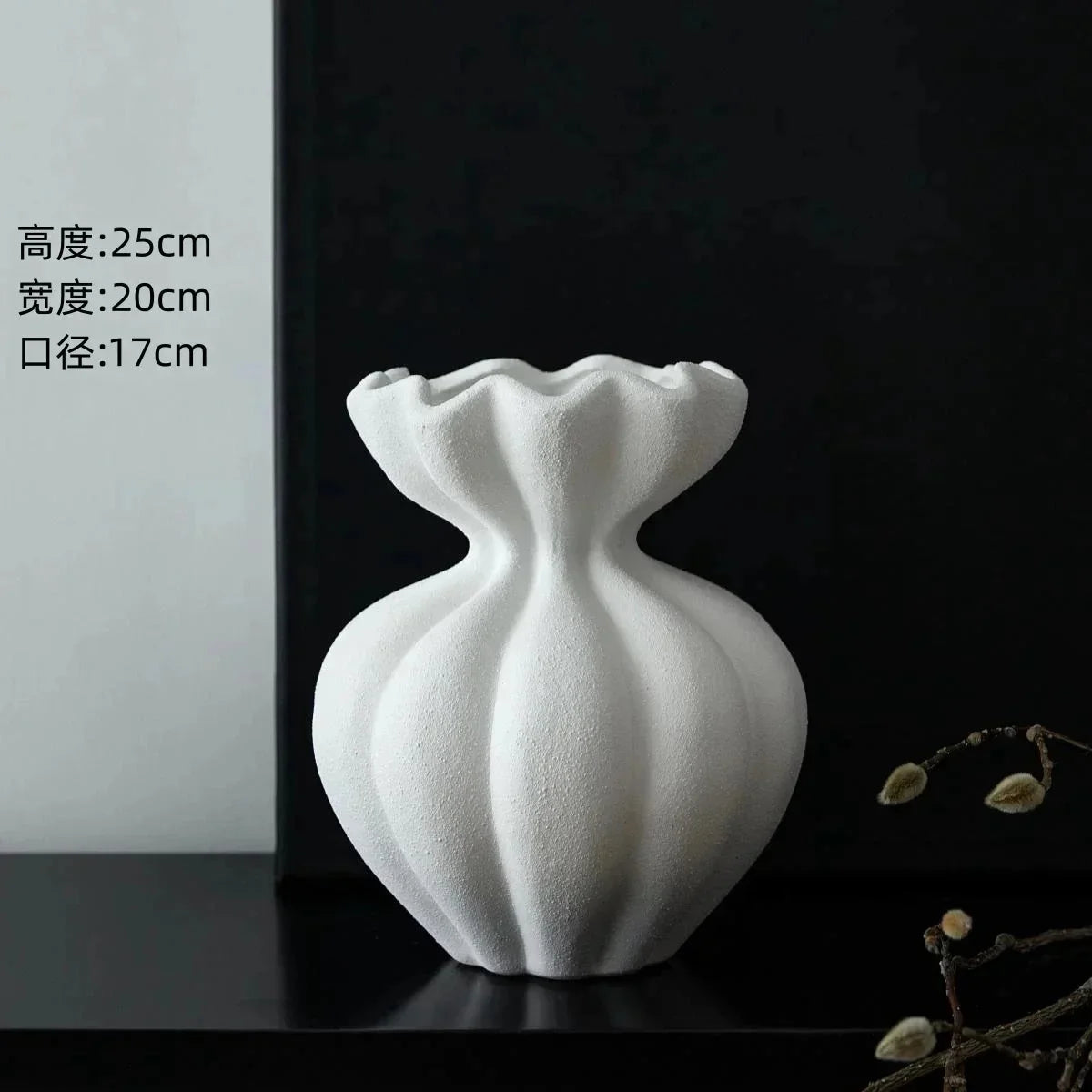White ceramic vase with a fluted neck and rounded body displayed on a dark surface.