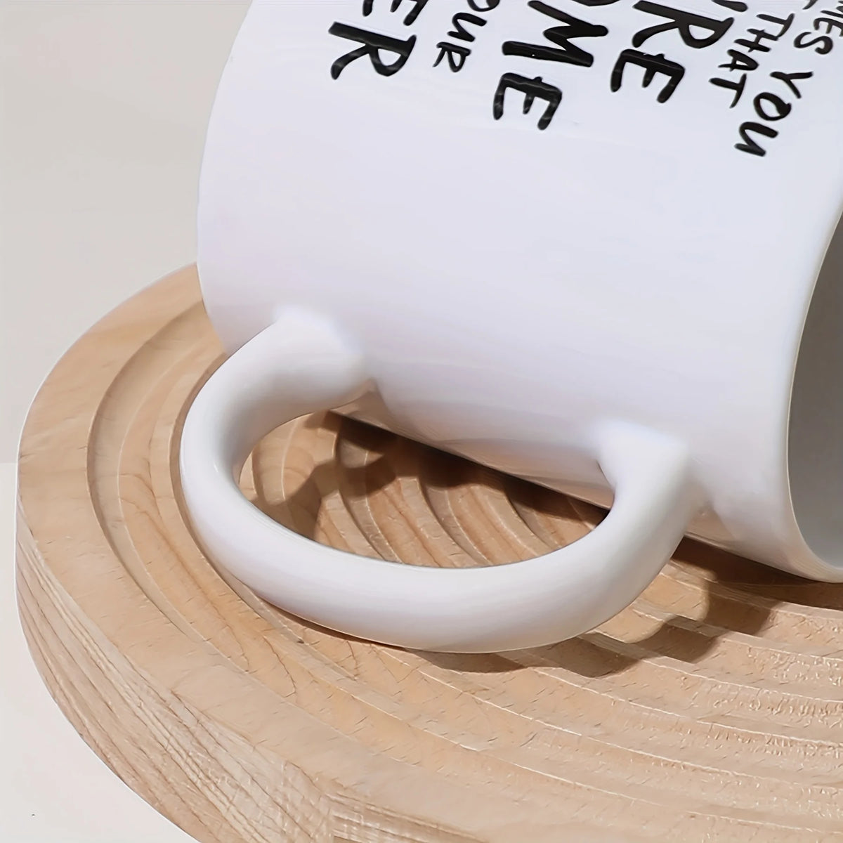 A white ceramic coffee mug with a handle rests on a light wooden cutting board.