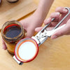 A hand is using an adjustable stainless steel jar and bottle opener to open a glass jar.