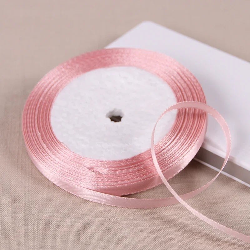 Pink satin ribbon spool with white fluffy material on a white background