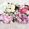 A lush artificial bouquet featuring pink and white roses and peonies on a light background.