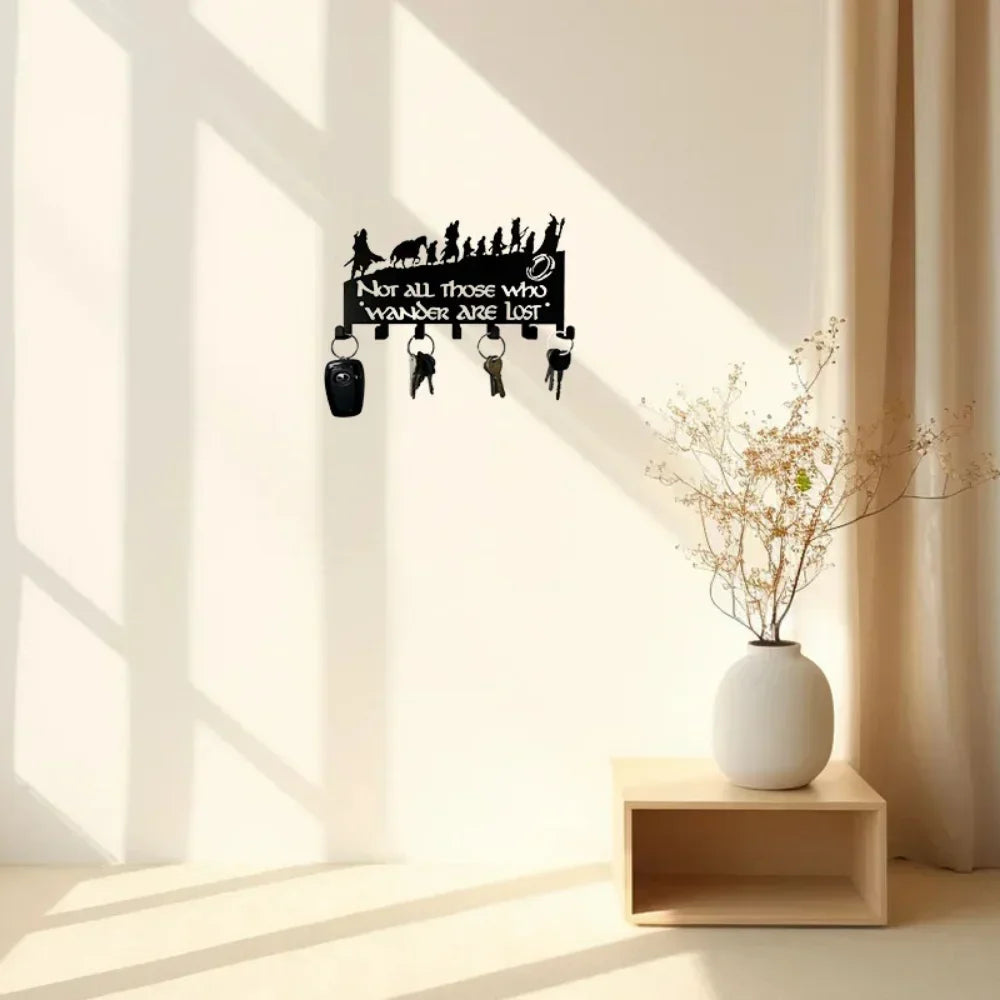 A black metal wall-mounted key holder with seven hooks is displayed on a light-colored wall.
