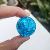 A hand holds a bright blue crystal ice crack ball used as water fountain decor.
