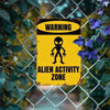 A vintage yellow warning sign with a black alien silhouette and text indicating an alien activity zone, set against a wire fe