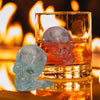 A silicone skull sphere and diamond ice mold set resting in a glass next to a warm fire.