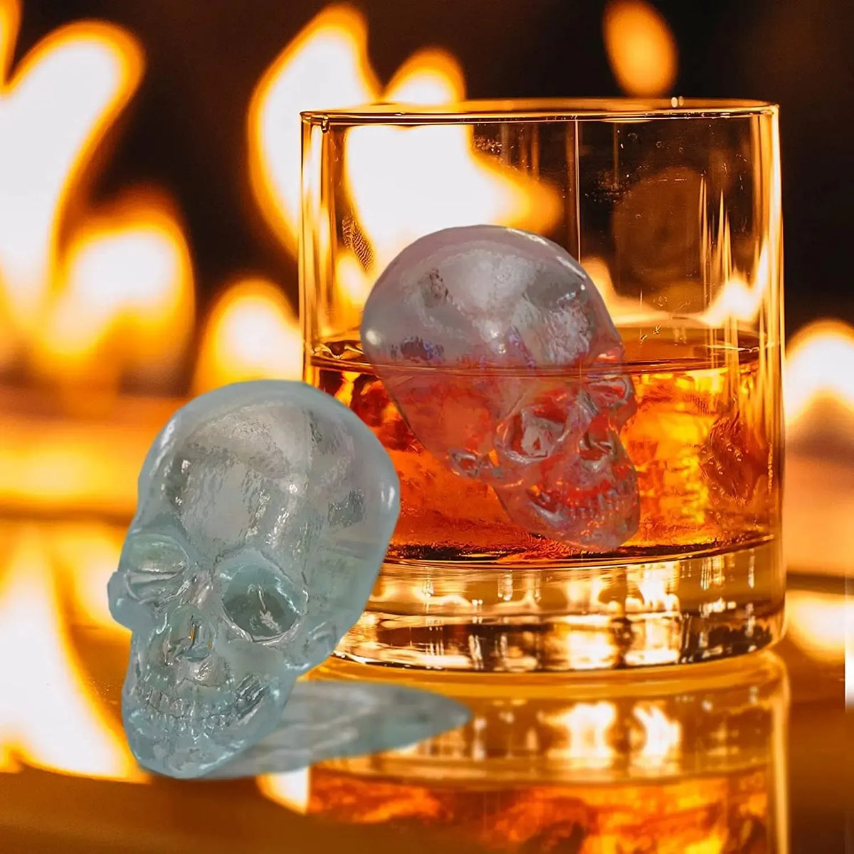 A silicone skull sphere and diamond ice mold set resting in a glass next to a warm fire.