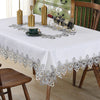 White tablecloth with silver lace trim set for a meal featuring a green cup and wine bottle.