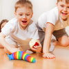 Two young boys are interacting with a colorful, flexible fidget slug toy on a wooden table.