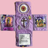 Handcrafted pocket devotional with a cross-shaped pouch featuring religious imagery on a purple fabric.
