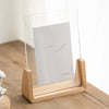 A walnut wood and acrylic photo frame displaying a minimalist line drawing on a light background.
