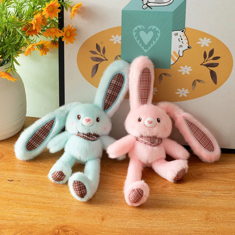 A pair of fluffy light blue and pink rabbit plush toys sitting on a wooden surface.