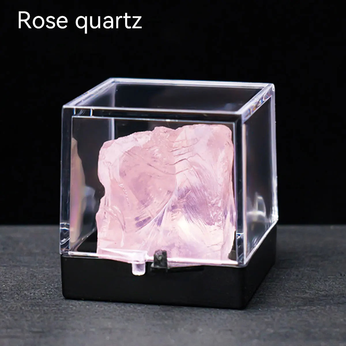 A rough pink rose quartz crystal specimen displayed inside a clear square box.