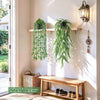 Four realistic hanging artificial ivy vines in various shades of green displayed on a white wall.