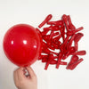 A hand holds a large red balloon and numerous red balloon shapes, including elongated pieces, against a white background.