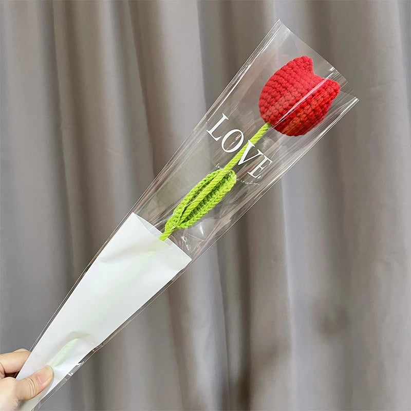 A handmade crochet tulip bouquet featuring a red flower and green stem, packaged in clear plastic.