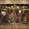 A rustic farm barn scene backdrop featuring wooden doors, hay, antique tools, and a guitar for a wild west birthday party.