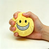 A hand is holding a yellow plush doll shaped like a smiling face with a wide toothy grin.