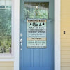 A vertical weathered wooden sign with white text listing camping rules like nap often, watch the sunset, and relax and unwind