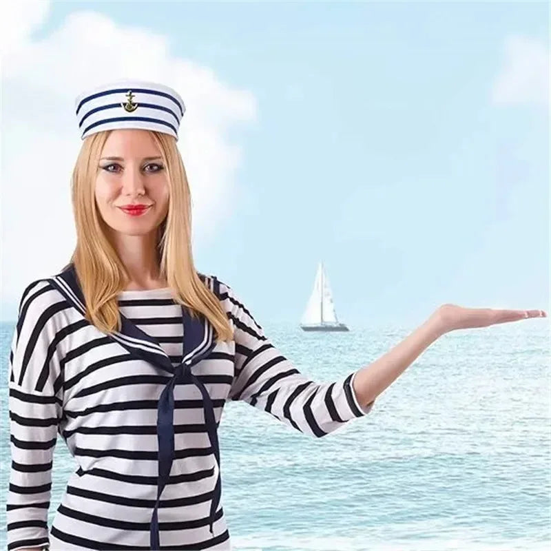 A blonde woman wearing a striped shirt and a captain's hat stands by the sea.