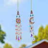 A pair of gold-toned crystal rhinestone sun catchers hanging against a bright blue sky and green foliage.