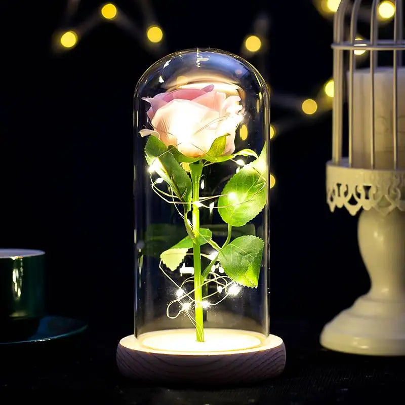 A glass jar containing a realistic rose plant illuminated by an LED light, set against a dark background.