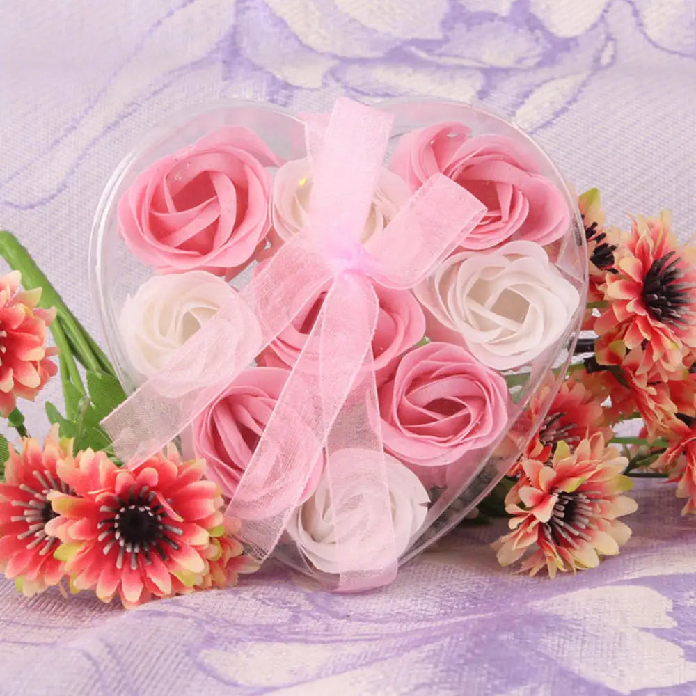 A clear plastic container holds a bouquet of handcrafted soap roses in shades of pink and white.