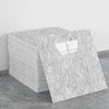 A rectangular slab of white marble tile sticker placed on a gray concrete floor.