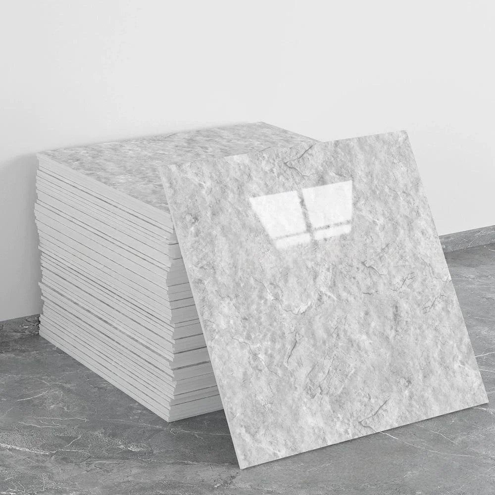 A rectangular slab of white marble tile sticker placed on a gray concrete floor.