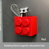 Red magnetic building block absorption box with stainless steel whisk and tongs mounted on a gray wall.