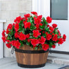 A vibrant potted artificial red azalea bush with green leaves displayed on a doorstep.
