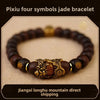 A dark brown bracelet featuring four jade symbols and an ornate gold-colored centerpiece.
