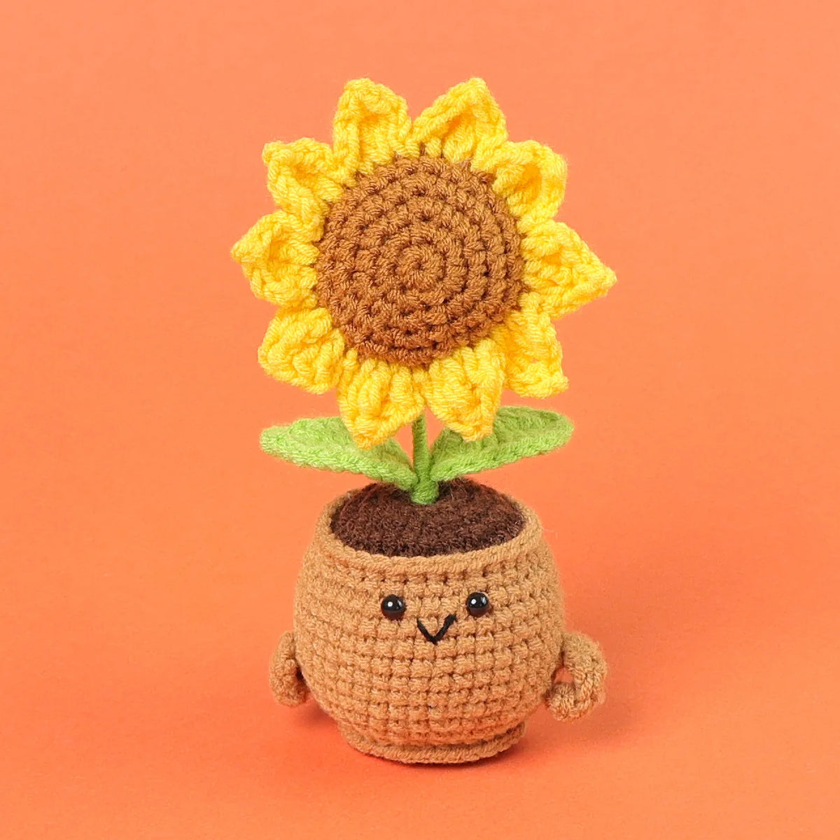 Handmade crochet sunflower desk companion with a smiling face, featuring yellow petals and a brown center.