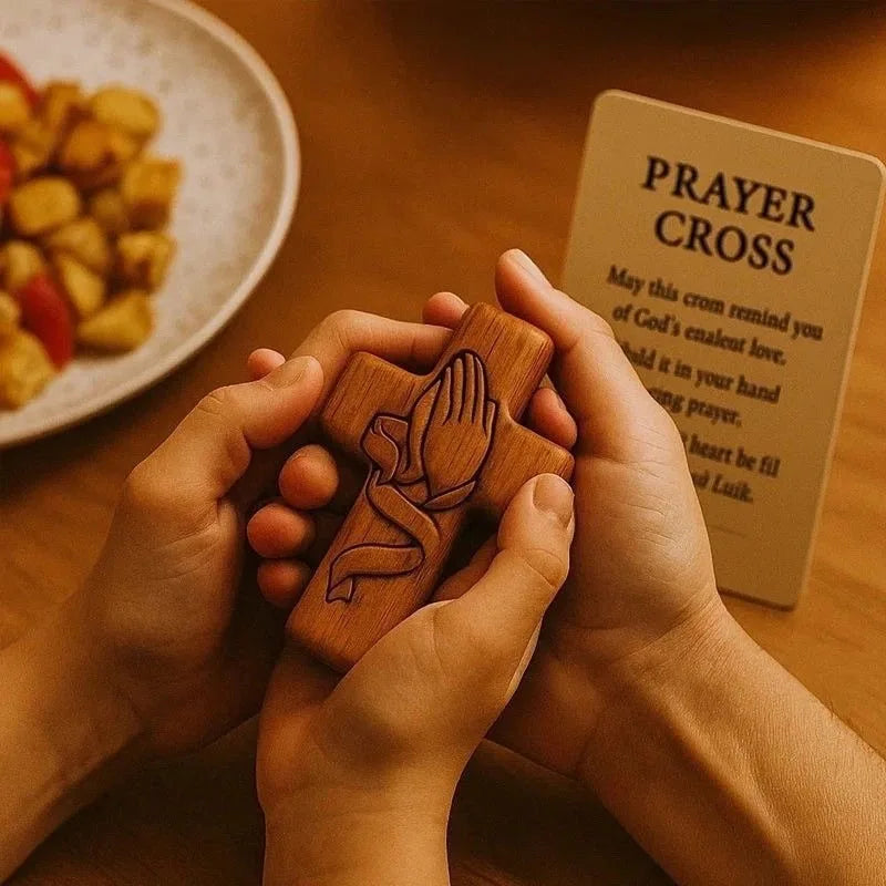 Two hands hold a handcrafted wooden prayer cross in front of a card that reads Prayer Cross