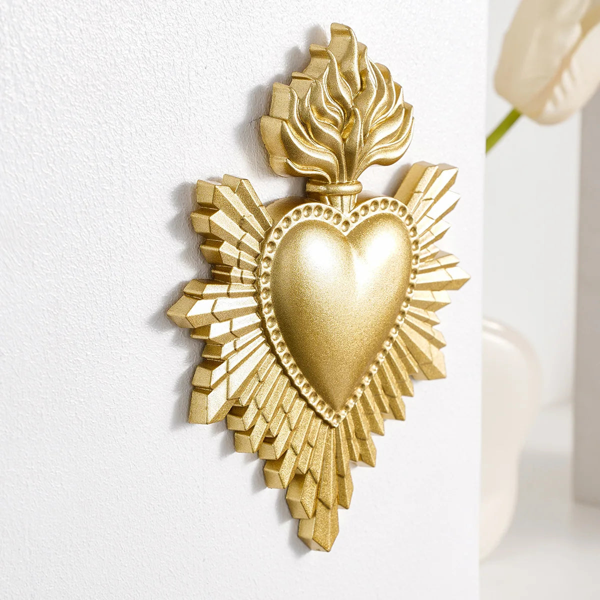 Gold resin wall decoration shaped like a heart surrounded by radiating flame-like leaves