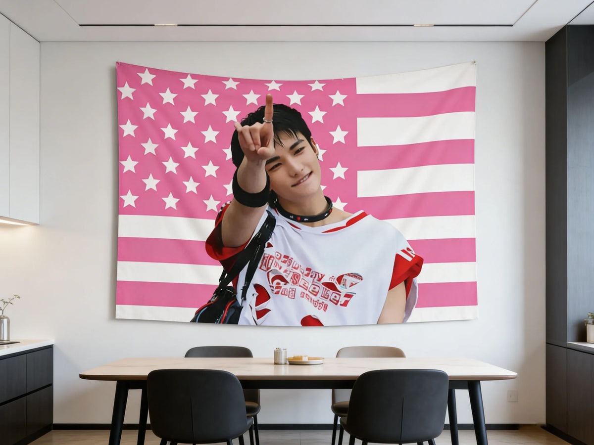 A photo of Hyunjin holding a pink American flag tapestry with a peace sign.
