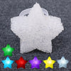 A collection of colorful star-shaped LED lights, including green, red, blue, purple, yellow, and silver, resting on a dark gr