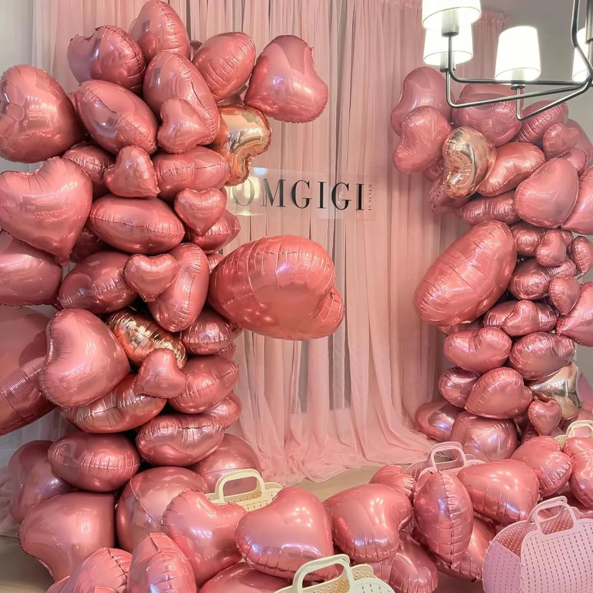 A large arrangement of pink heart-shaped foil balloons clustered together for a party decoration.