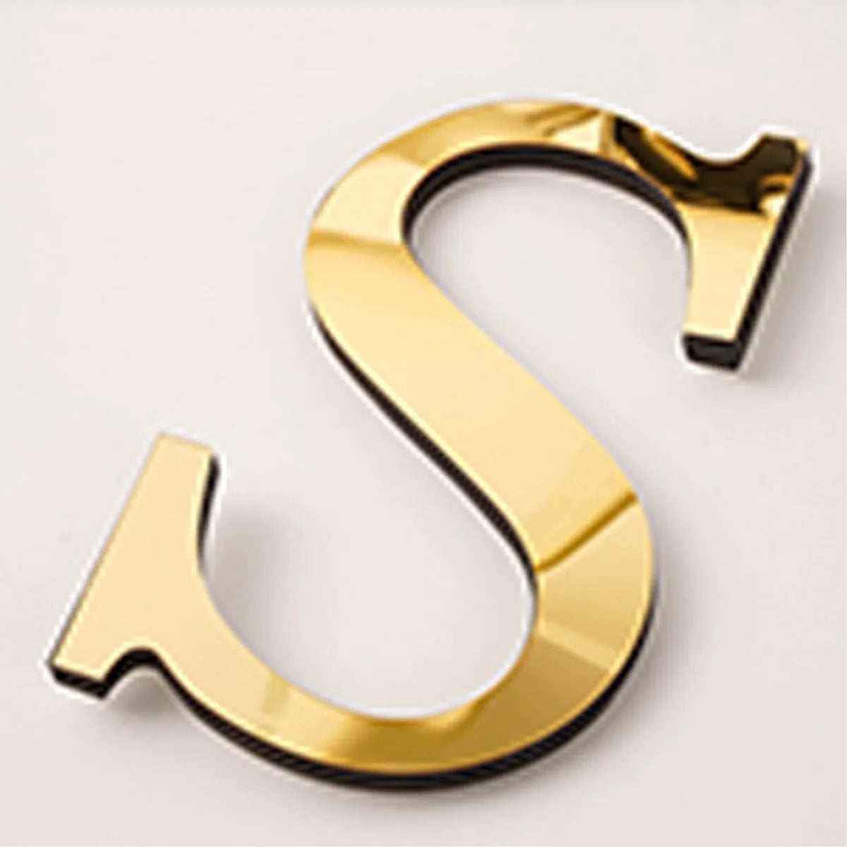 A shiny gold acrylic mirror letter S wall sticker for decorative purposes.