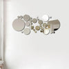 A collection of various sized, circular 3D acrylic mirrors arranged in an organic, scattered pattern on a white wall.