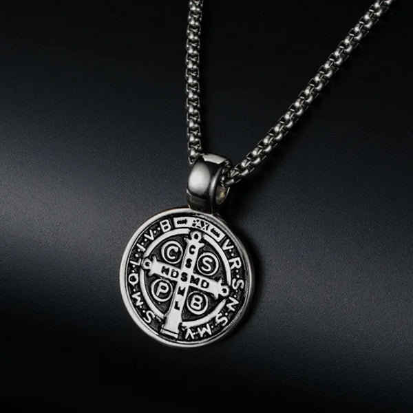 A silver stainless steel medal necklace featuring a cross design and Latin letters, suspended from a chain.