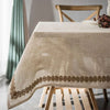 A beige stretch spandex tablecloth with a decorative brown floral border on a wooden table.