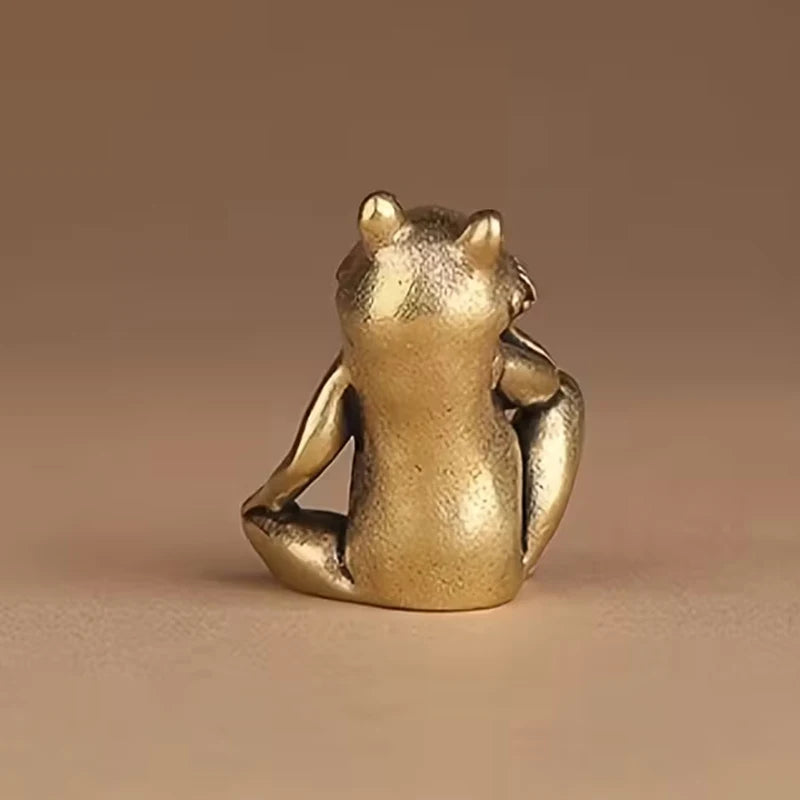 A vintage brass frog statue ornament sitting on a neutral background.